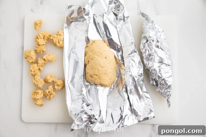 Seitan dough meticulously wrapped in aluminum foil, prepared for steaming.