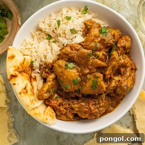 Restaurant-style chicken curry served over basmati rice with naan in a white bowl