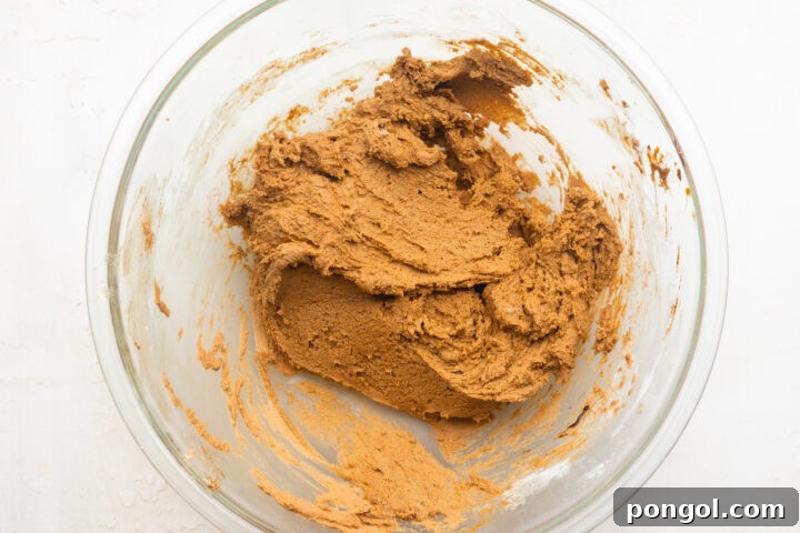 Gluten-free gingerbread cookie dough in a large glass mixing bowl.