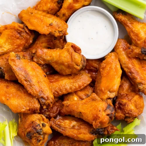 A large plate filled with Whole30 buffalo wings, celery stalks, and a small ramekin of Whole30 ranch dressing.