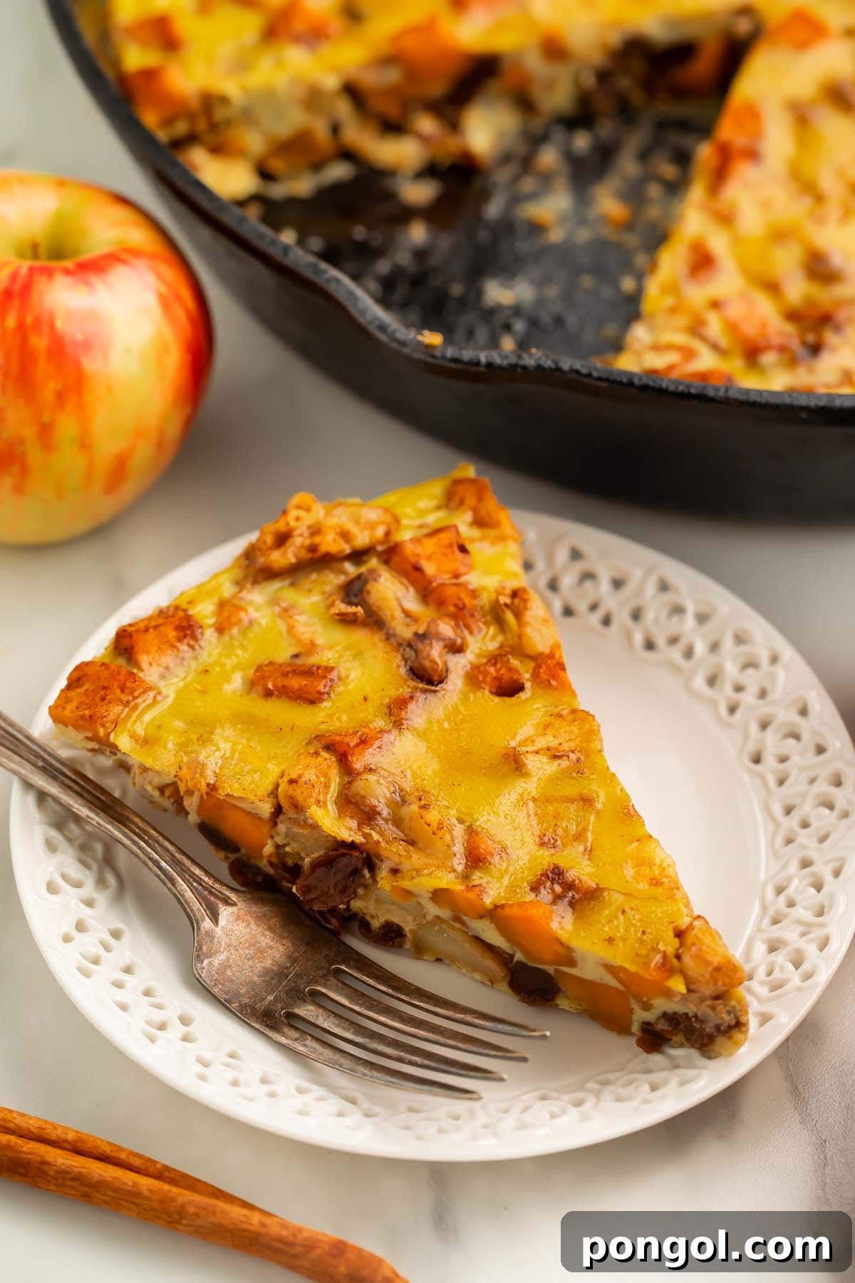 Paleo Harvest Breakfast Bake with Sweet Potatoes and Apples 3 A triangular wedge of paleo breakfast bake on a small white plate with a fork.