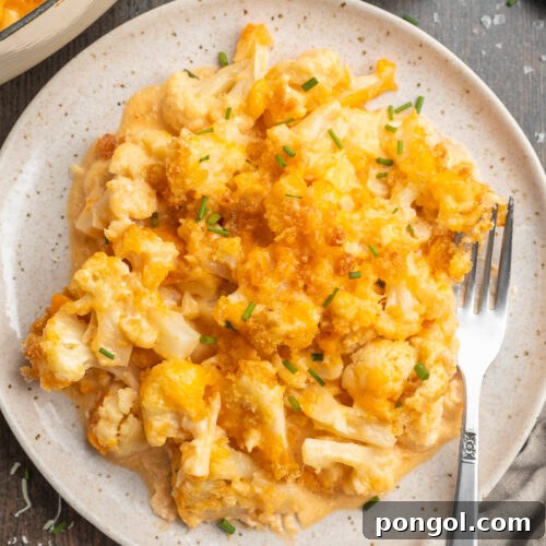 Overhead view of keto mac and cheese plated on a serving plate with a fork on a dark table.