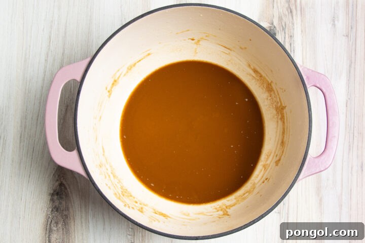 Rich, deep, dark brown roux made from butter and flour in a large heavy-bottomed pot with two handles.