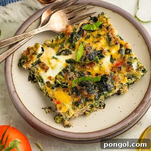 Savory Whole30 Keto Sausage and Egg Breakfast Bake 4 Slice of Whole30 breakfast bake with sausage, eggs, spinach, and bell peppers on a cream plate with a fork