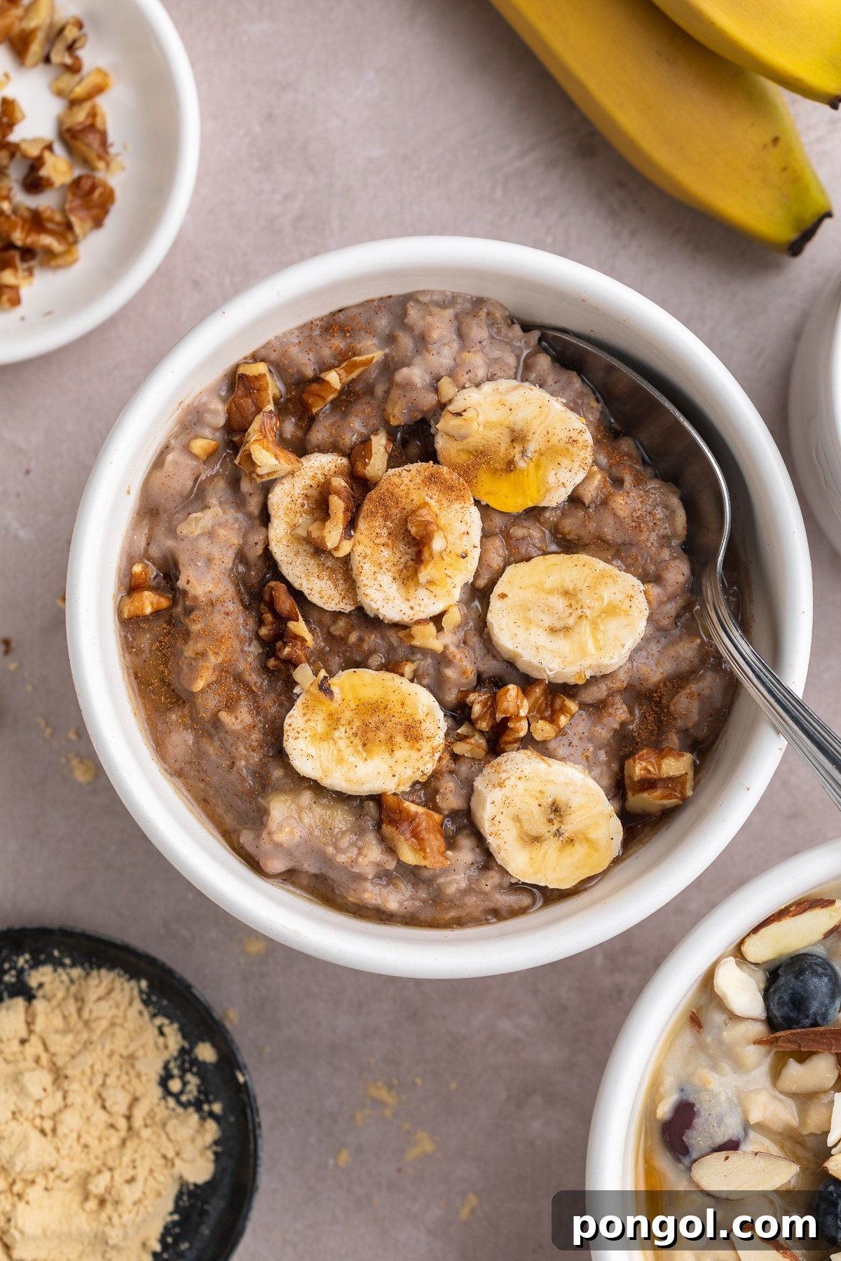 Protein Power Bowls: 3 Creative Oat Recipes 3 Close-up overhead photo of banana nut protein oatmeal in a small white ramekin with a silver spoon.