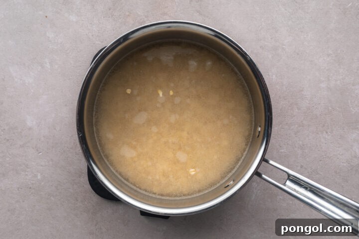 Uncooked, dry rolled oats in a silver saucepan with a single handle, with water covering the oats.