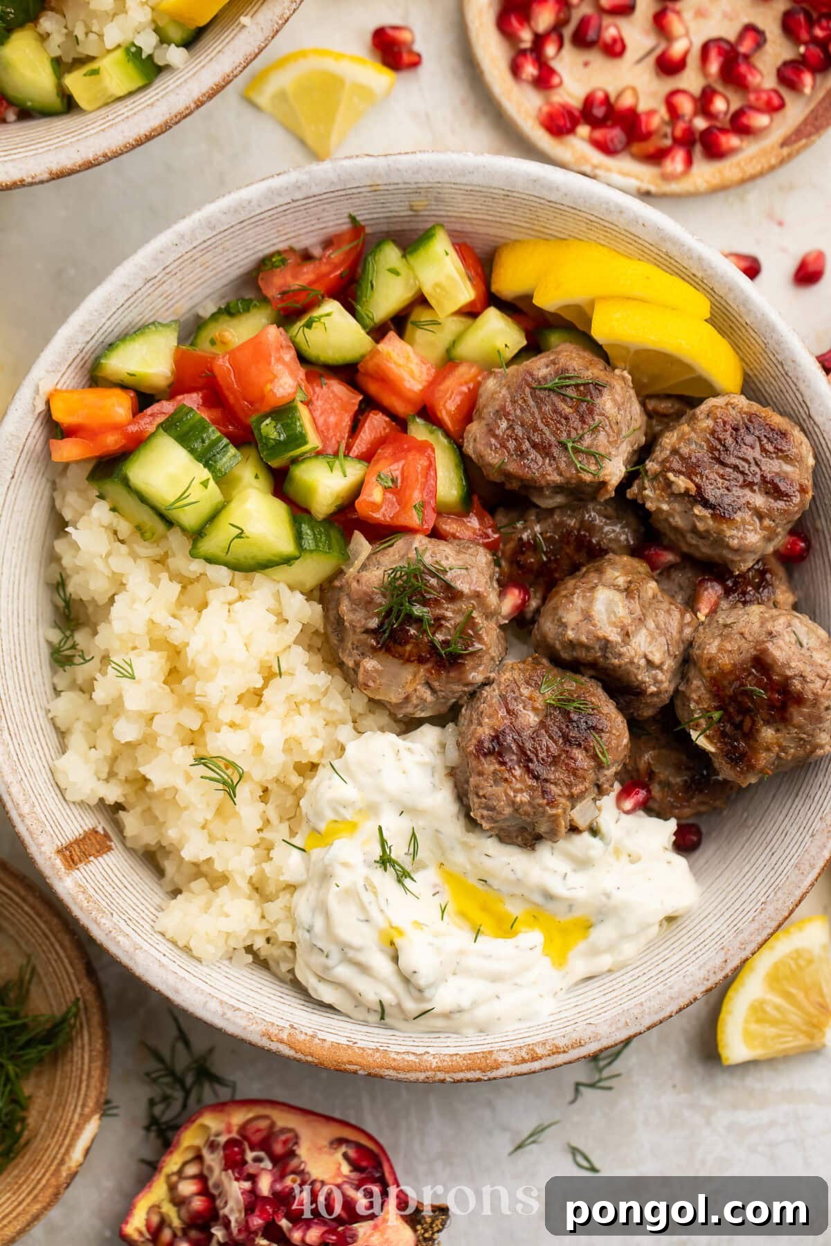 Whole30 gyro meatballs in a large bowl with tabbouleh, cucumber salsa, cauliflower rice, and Whole30 tzatziki.