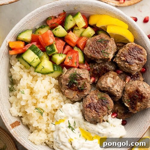 Whole30 gyro meatballs in a large bowl with tabbouleh, cucumber salsa, cauliflower rice, and Whole30 tzatziki.