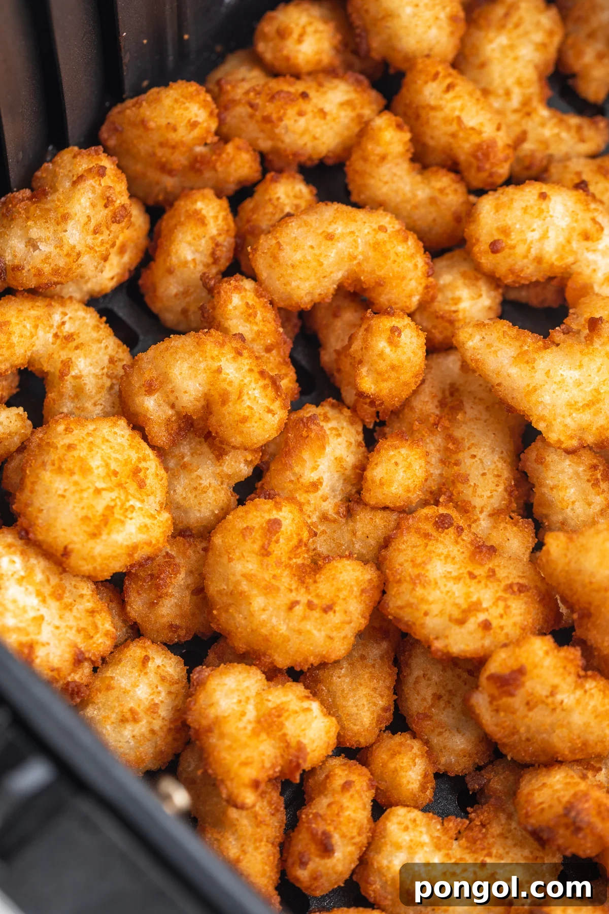 Golden Crispy Air Fryer Popcorn Shrimp 3 Close-up look at golden, crispy, air fried popcorn shrimp in an air fryer basket.