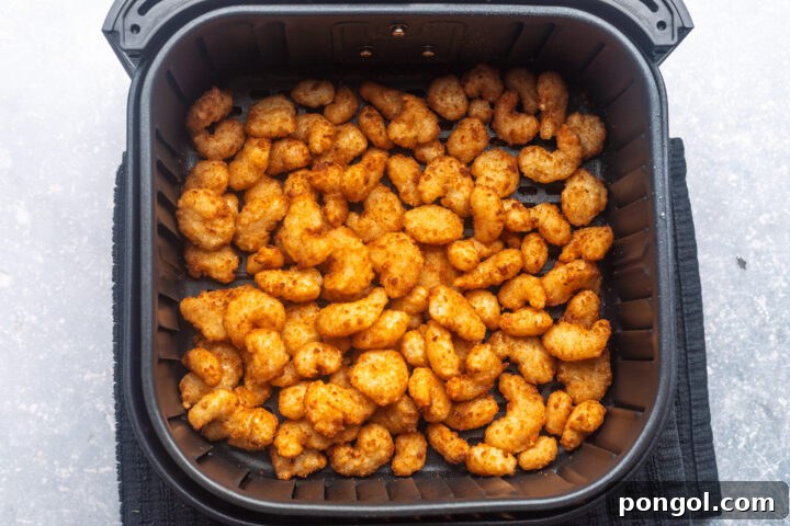 Frozen popcorn shrimp in the air fryer basket, cooked until golden and crispy.