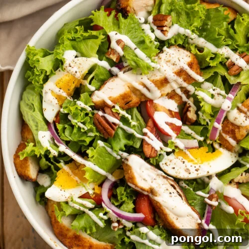 Whole30 southern fried chicken salad with lettuce, fried chicken, red onion, eggs, pecans, and ranch dressing.