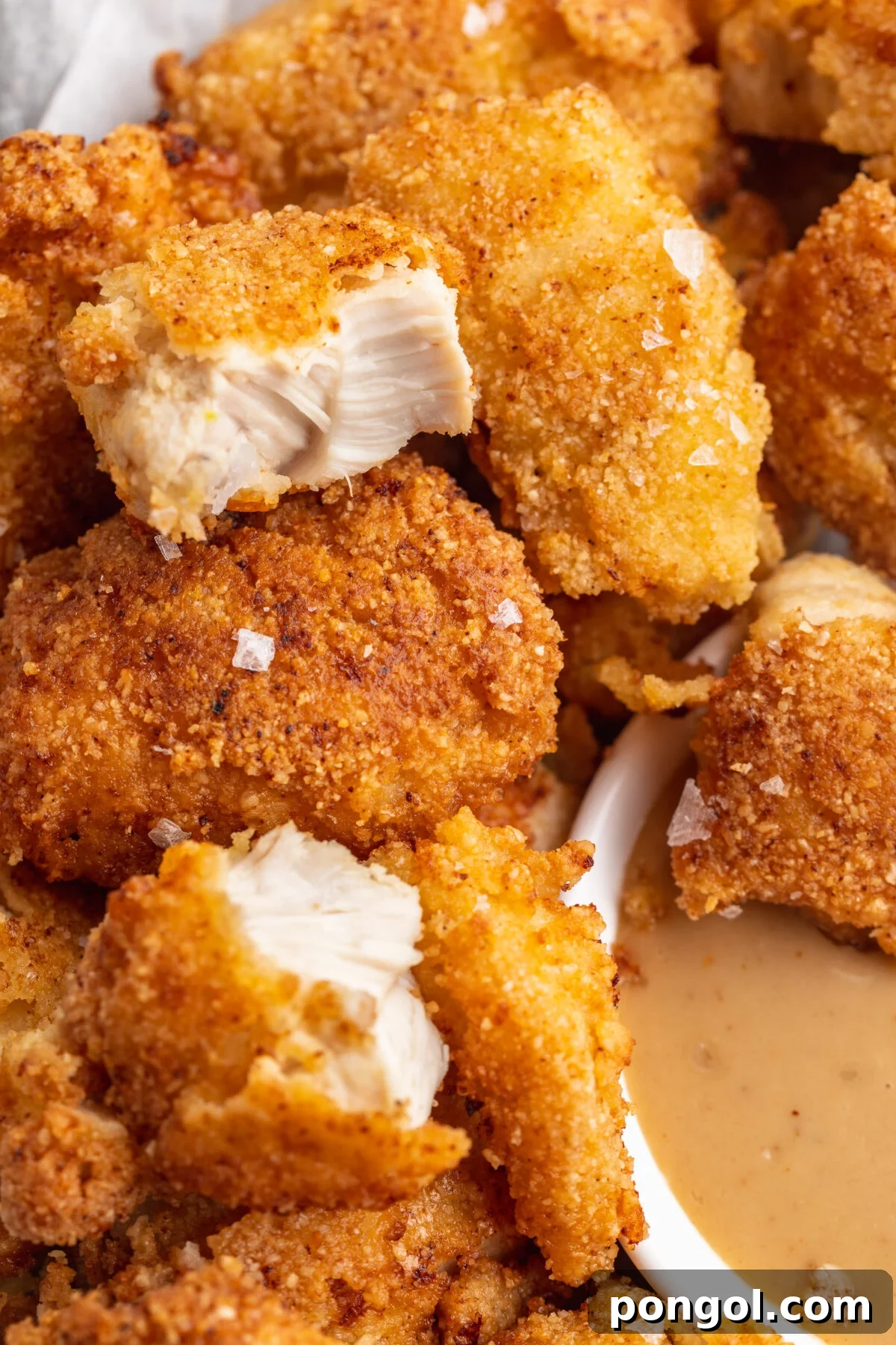 Close up of keto chicken nuggets, with one nugget cut in half to show cross section.