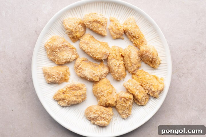 Keto chicken nuggets, breaded but not yet fried, on a white plate.