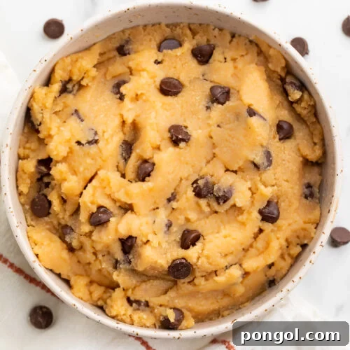 Keto cookie dough in a large bowl with keto chocolate chips sprinkled around the bowl.