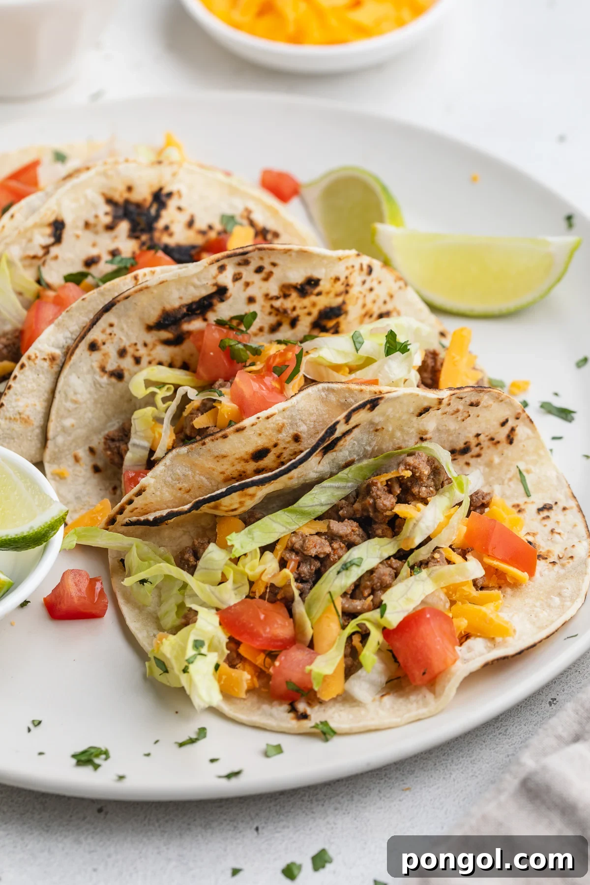 Keto Tacos From Scratch: Homemade Low-Carb Tortillas 3 Zoomed out look at several delicious keto tacos lined up on a plate, ready for serving.