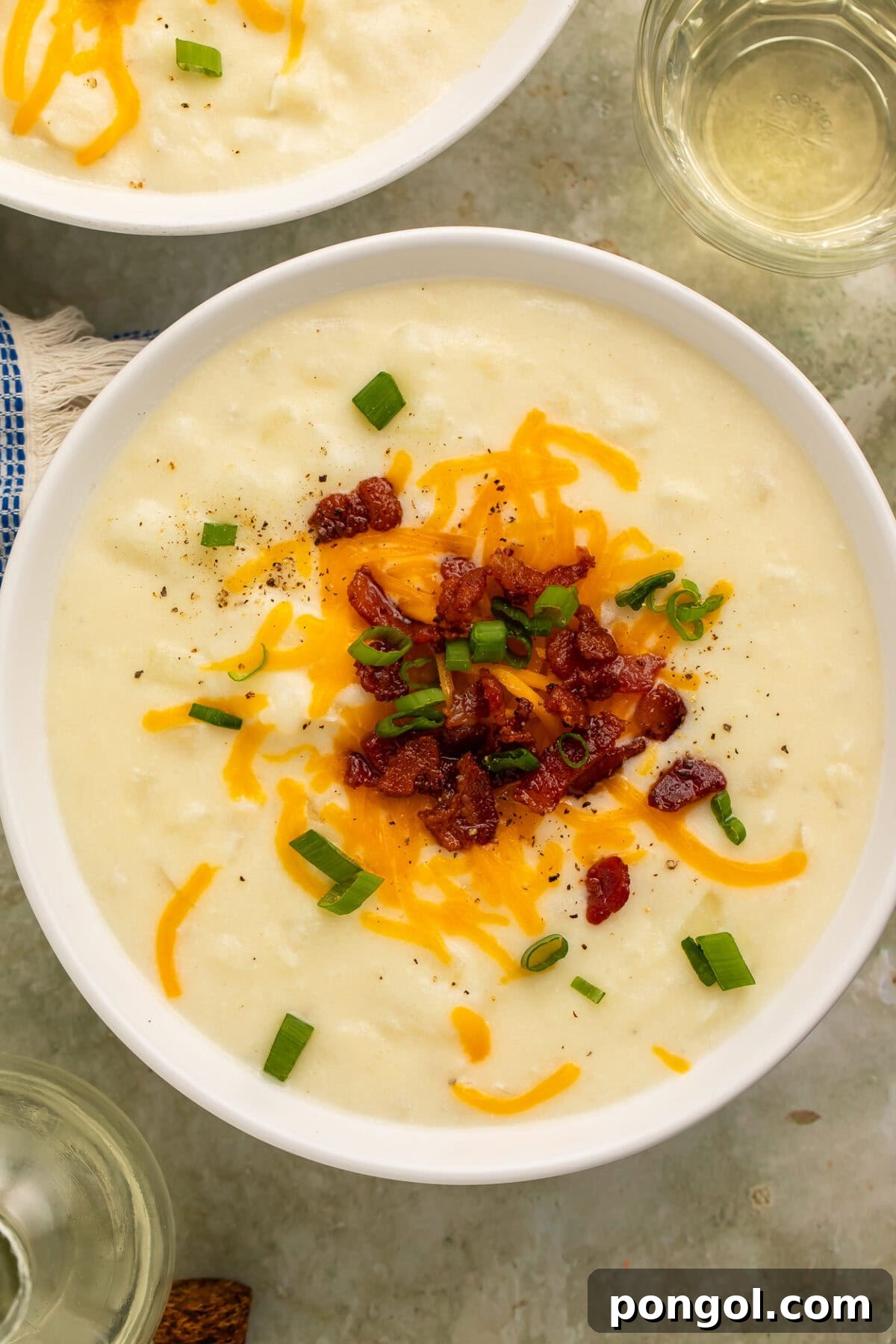 Creamy Country Potato Soup 2 Creamy old-fashioned potato soup in a white bowl topped with shredded cheddar cheese, bacon, and green onions, capturing a cozy, comforting scene.
