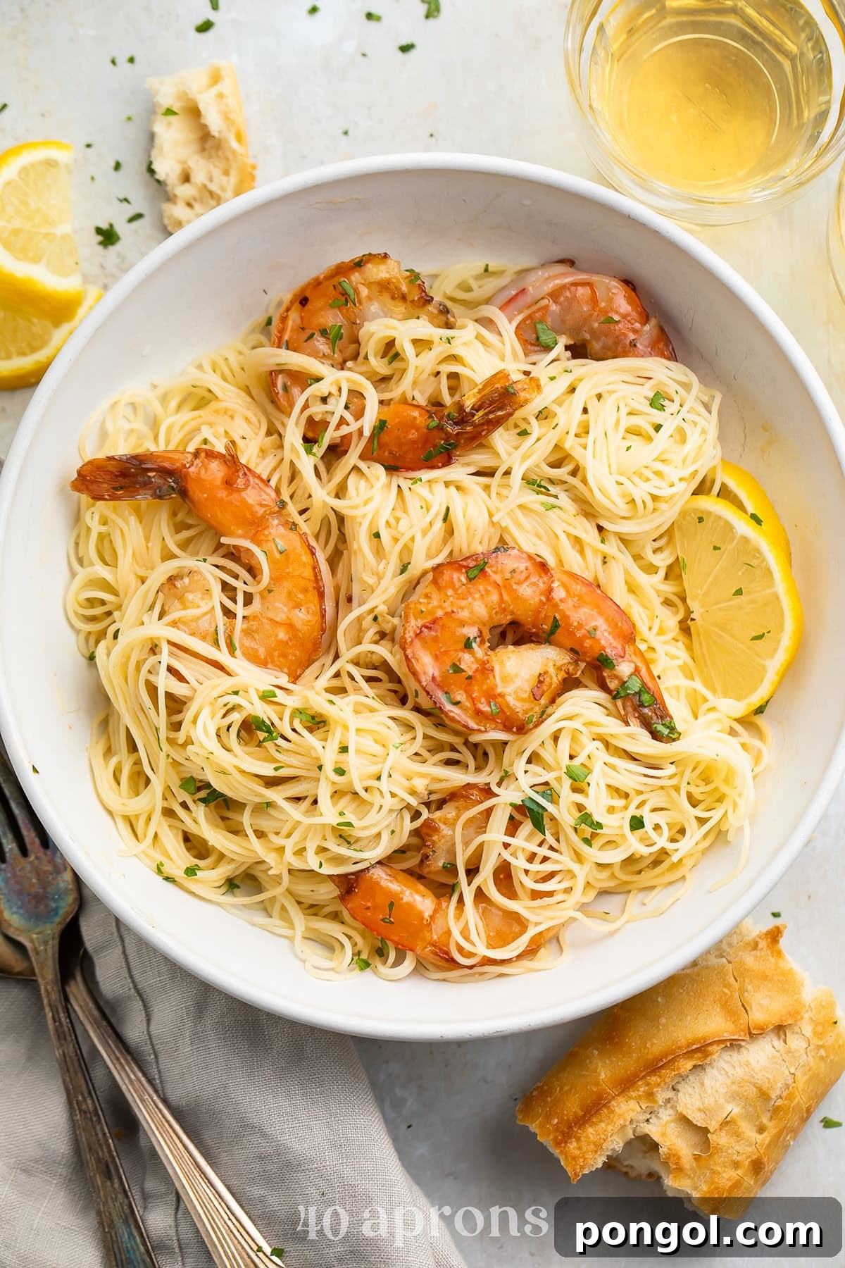 Garlic Butter Shrimp Sauté 3 Sautéed garlic butter shrimp plated atop a bowl of angel hair pasta and garnished with parsley and lemon wedges.