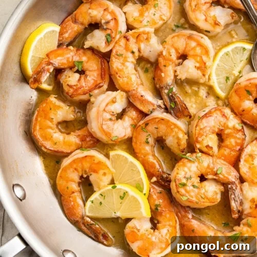 Garlic Butter Shrimp Sauté 4 Sautéed garlic butter shrimp in a large silver skillet with lemon and parsley.