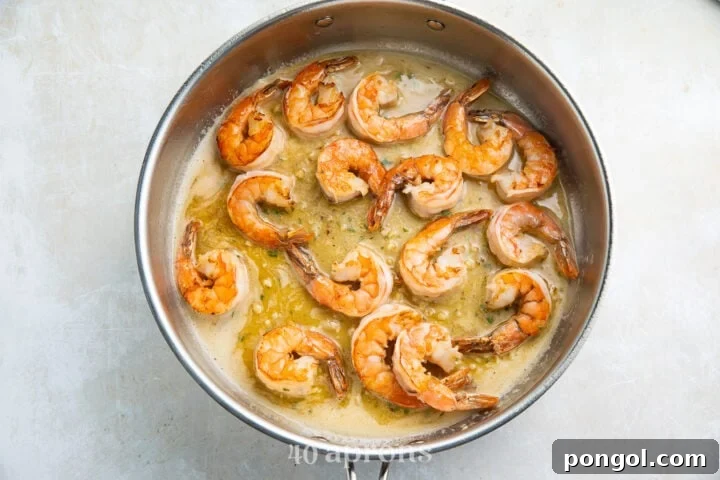 Sauteed shrimp in garlic butter sauce in a silver pan.