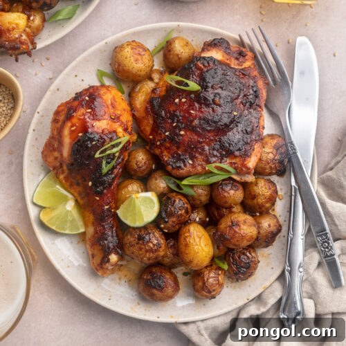 Sweet and Spicy Gochujang Sheet Pan Feast 4 A close-up view of a serving of gochujang chicken and potatoes on a white plate, showcasing its rich color and texture.