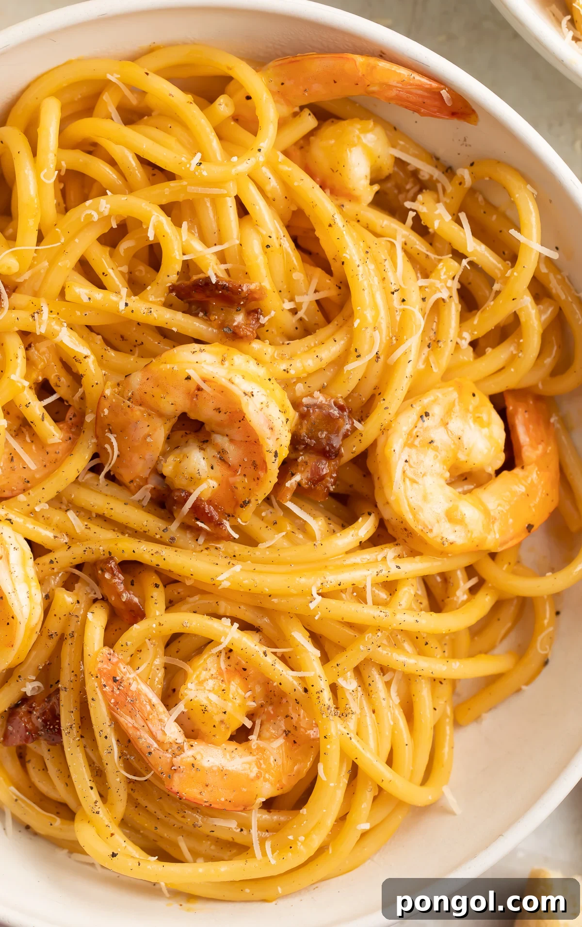 Close-up view of shrimp carbonara in a large white pasta bowl, showcasing the creamy sauce and plump shrimp.