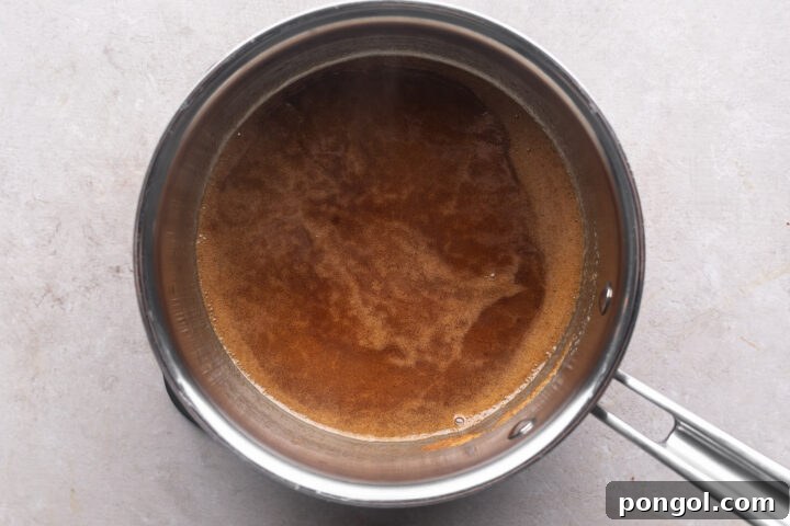 Brown swerve and melted butter in a silver saucepan on a neutral countertop.