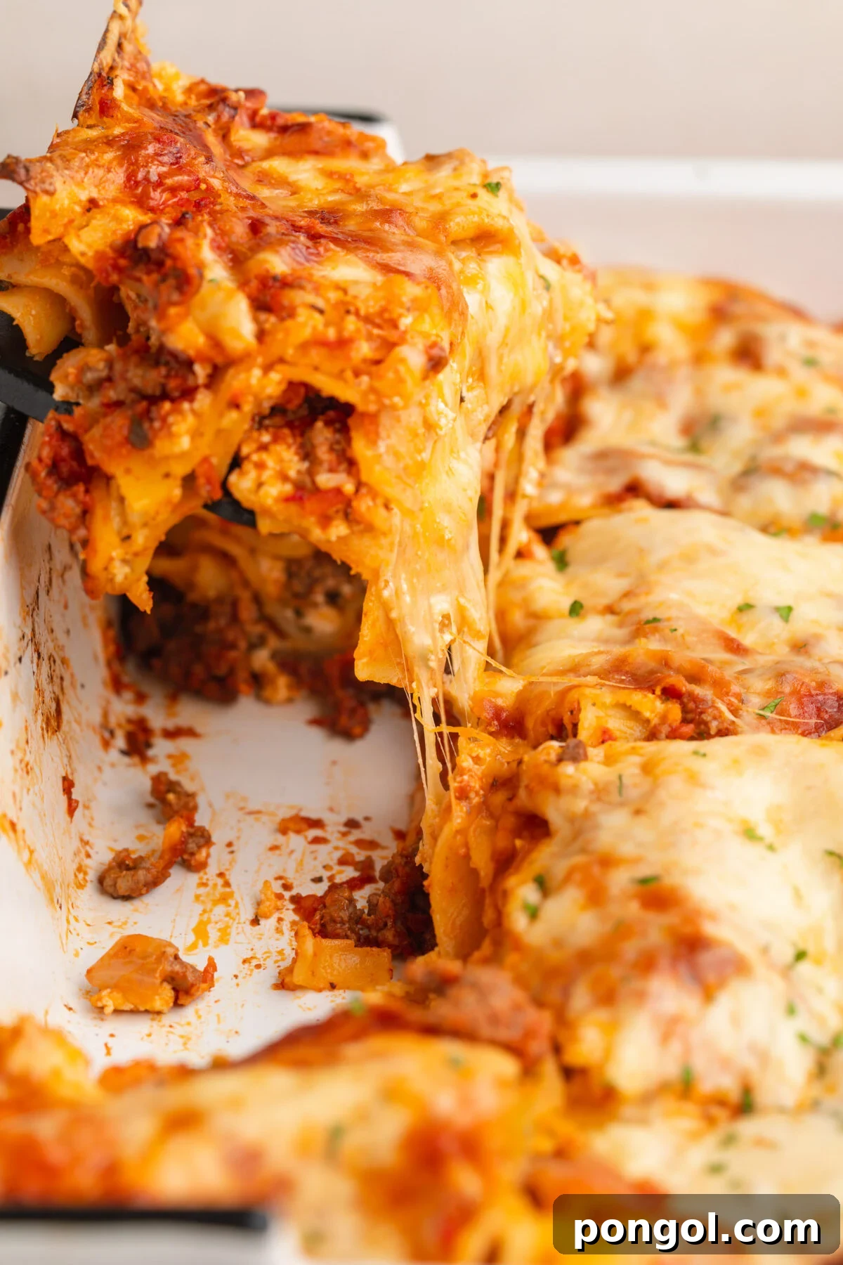 Irresistible Gluten-Free Lasagna 2 A square of perfectly baked gluten-free lasagna being lifted out of a casserole dish, revealing its rich layers.