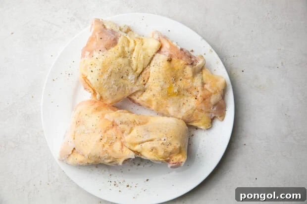 Raw chicken thighs on a white plate