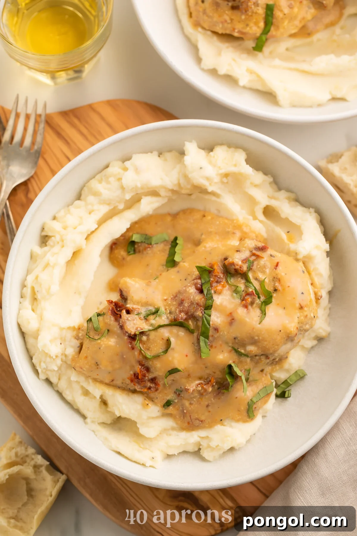 Top-down, overhead view of a Crockpot-cooked marry me chicken breast with sauce atop a bed of mashed potatoes in a large white bowl.