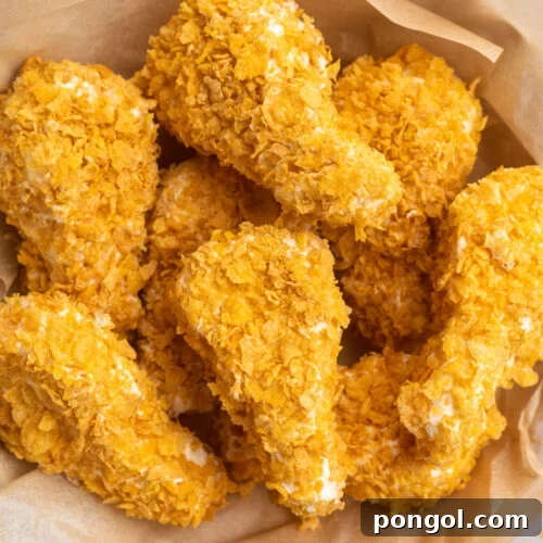 Overhead, top-down view of fried chicken ice cream drumsticks in a bowl lined with parchment paper.