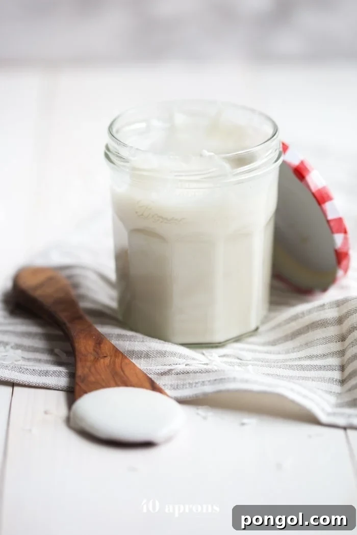 A bowl of freshly made coconut butter, with a spoon resting in it, showcasing its rich, dense, and aromatic texture, ready to be enjoyed.