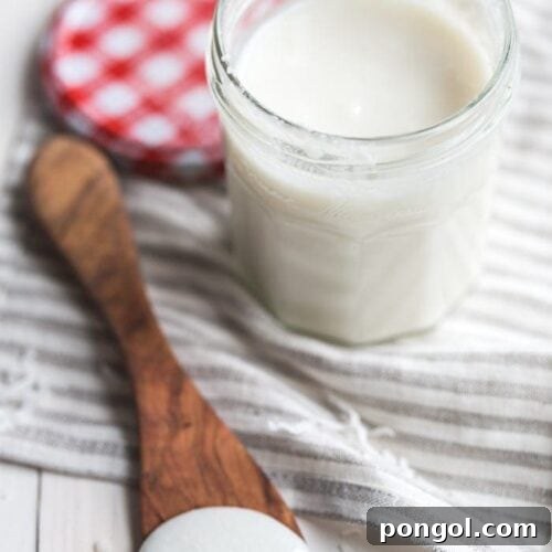 A jar of homemade coconut butter, with a spoon dipped in, highlighting its creamy texture.