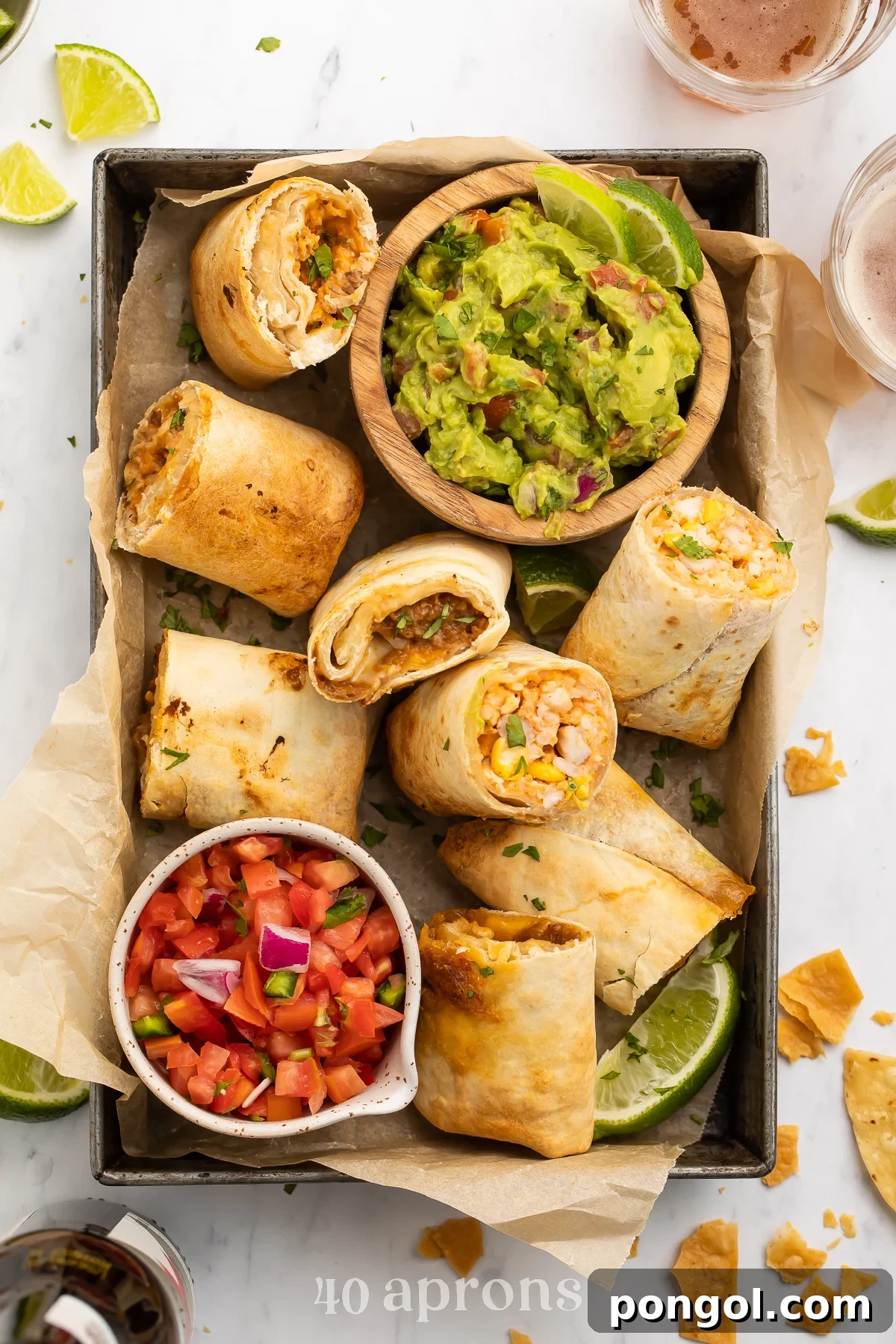 Top-down view of frozen burritos cooked in the area fryer, halved and arranged in a baking pan with guacamole and fresh salsa.