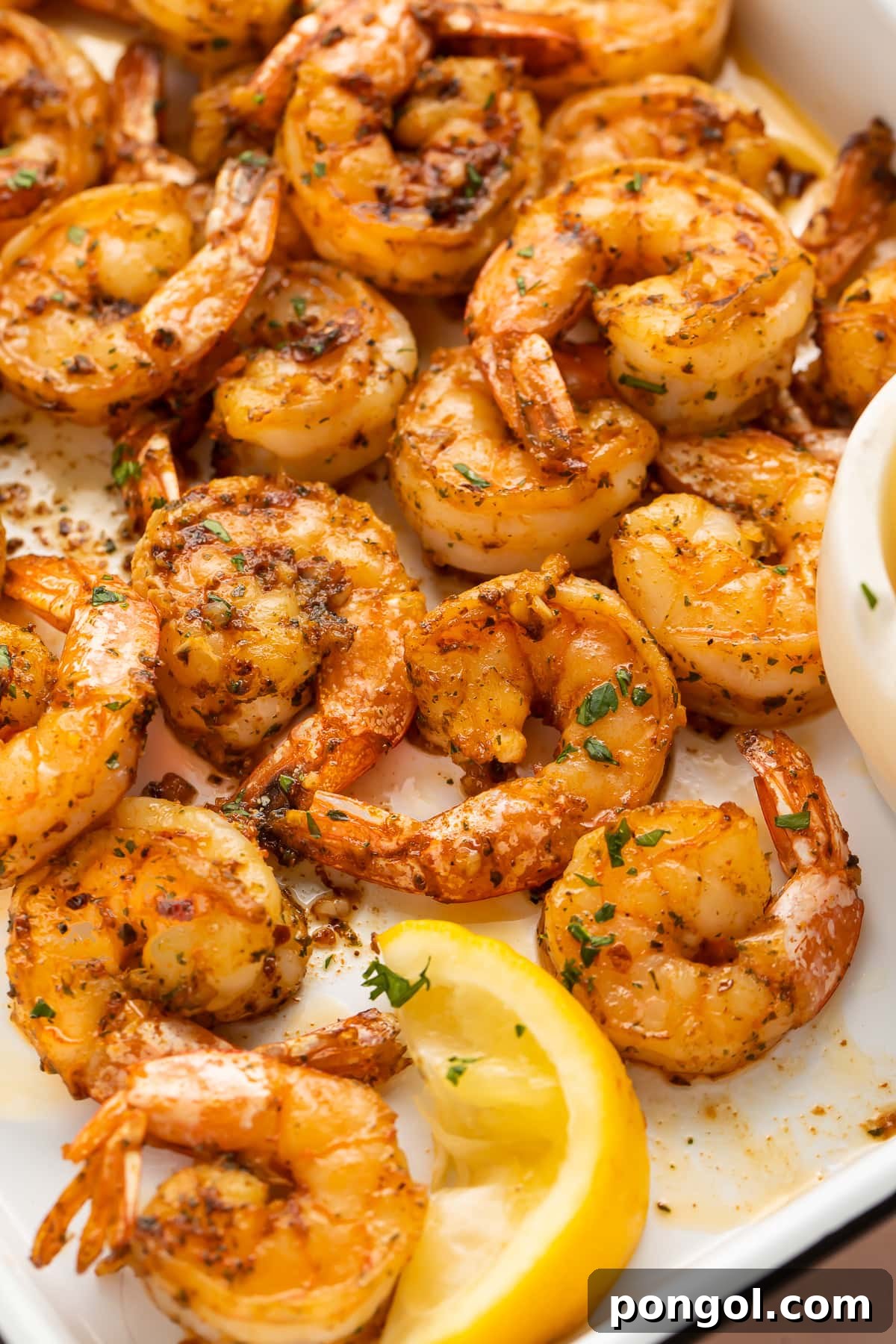 Close-up of garlicky broiled shrimp on a platter.